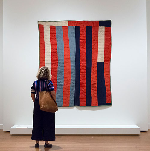 gallery visitor examines a quilt