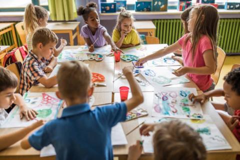 group of children at a table all painting