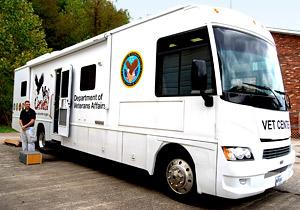 White bus labeled with black letters VET CENTER and Department of Veterans Affairs. A person is standing in front of an open side door.