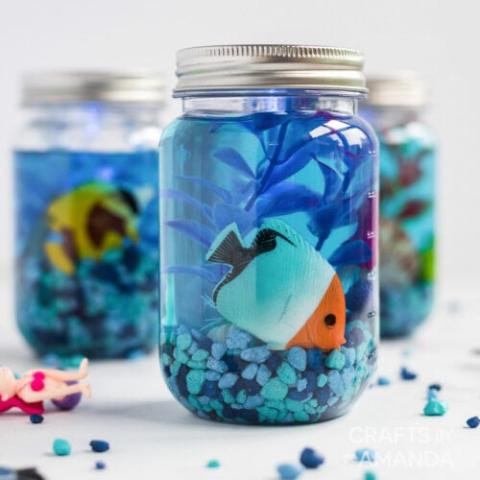 A mason jar filled with water and a toy fish and aquarium items