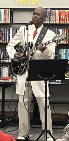 Kenneth Jackson playing his black hollow body Gibson guitar. 