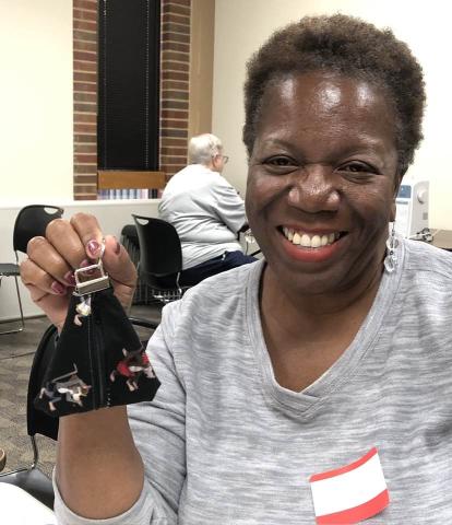 Happy adult holding small zipper bag she made in the sewing class at the Cherokee Library.