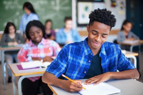 Students writing in a classroom setting.