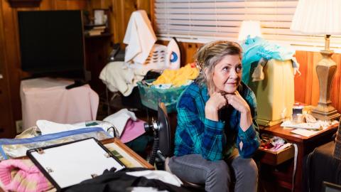 older woman in messy room, disorganized, stuff, blue shirt