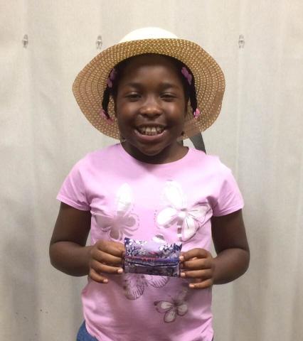 Tween with a hat holding a small sewing project