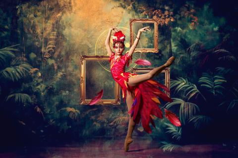 ballet dancer in full Firebird costume presenting a ballet pose with a jungle themed background