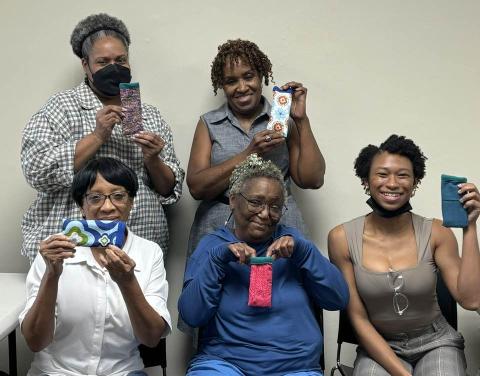 Five happy adults show off their new, finished sewing projects.