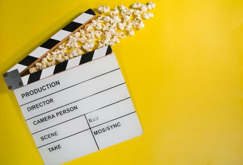 A film clapperboard with popcorn around it