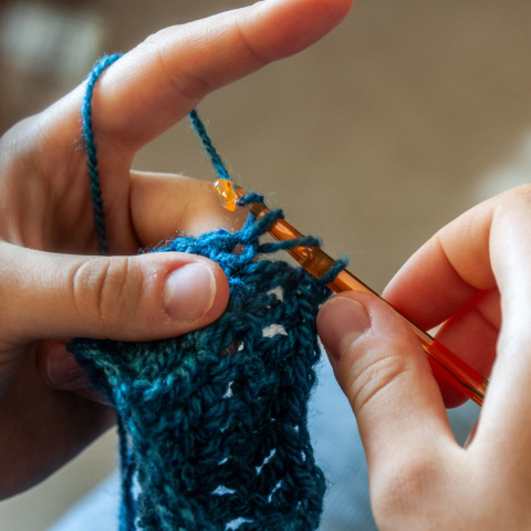 fingers crocheting blue yarn