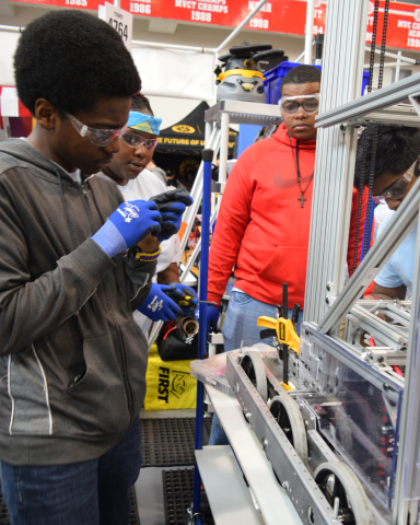 Members of the robotics team fixing a robot they built.