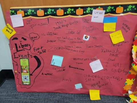 Red poster board with writing describing children's Halloween costumes.