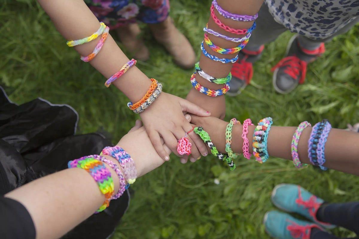 four hands put into the center, stacked on top of each other. Each arm has several friendship bracelets 