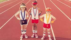 photo of three children on a track wearing running gear with medals around their necks