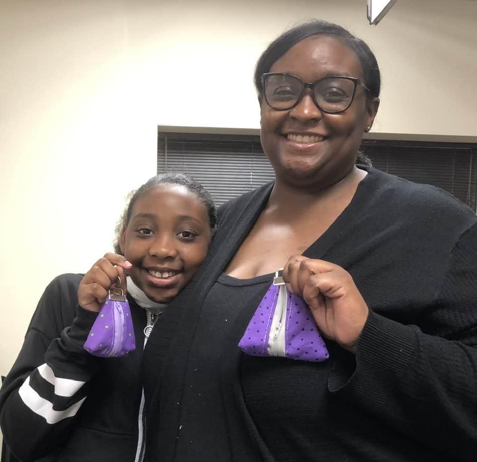 Adult and daughter showing off the zipper pouches they created in the sewing class.