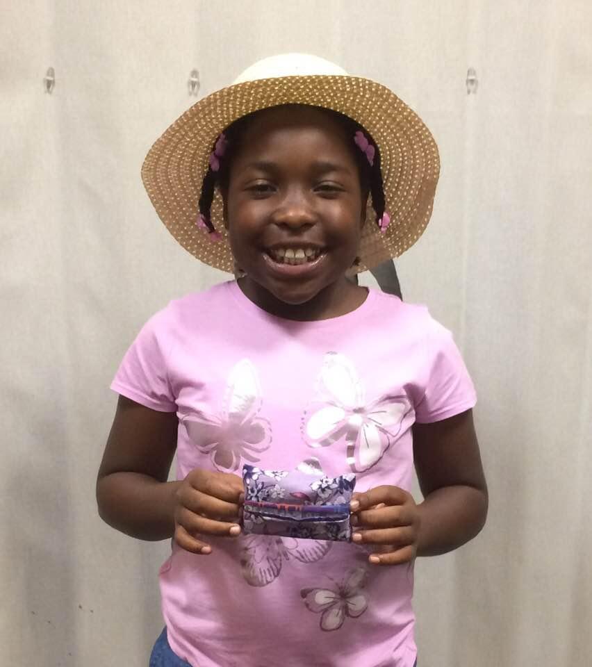 Tween with a hat holding a small sewing project