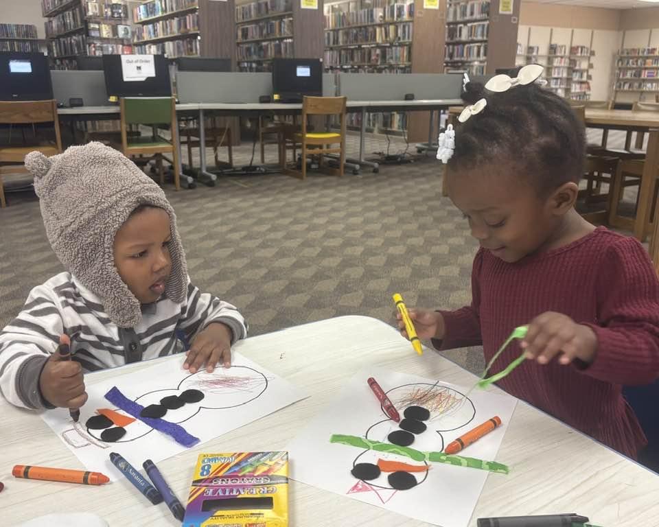 Two toddlers in Cherokee Library, working on a snowman picture.