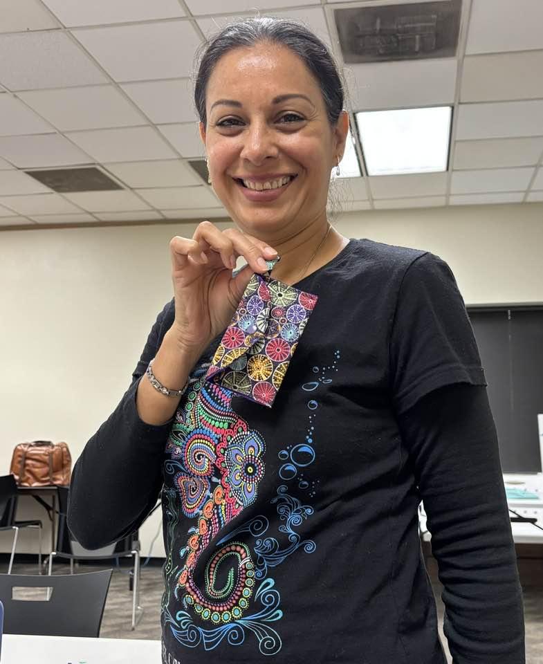 Woman in black t-shirt poses with her finished project, a credit-card sized snap wallet.